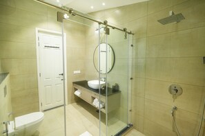 Une salle de bain moderne avec une douche à parois de verre, des toilettes blanches et un lavabo avec un miroir au-dessus.