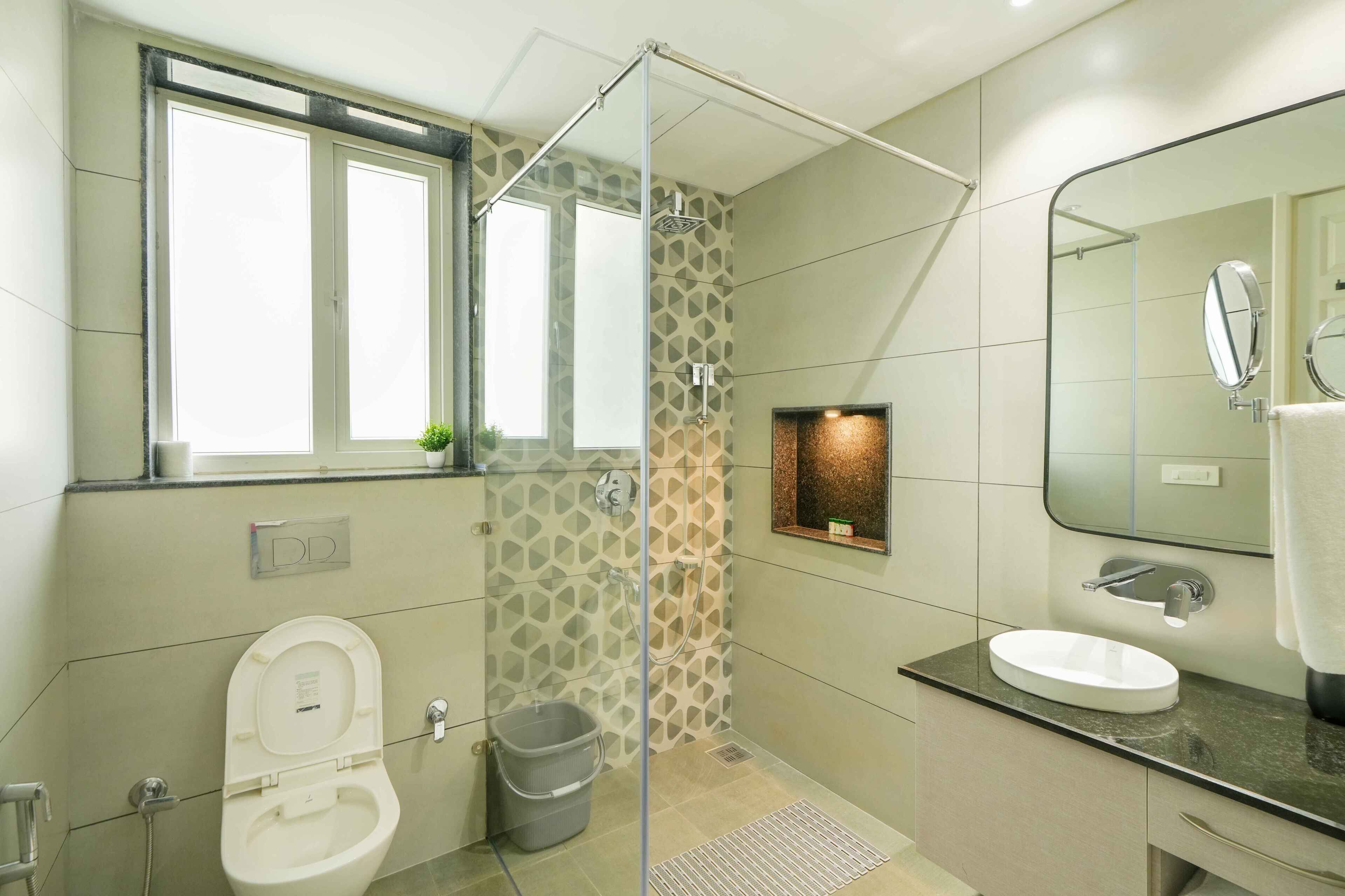 Ein modernes Badezimmer mit Duschkabine aus Glas, Toilette, Waschbecken und einem großen Spiegel.