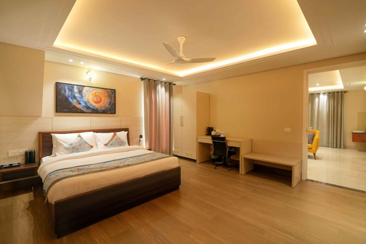 A modern hotel room with a large bed, desk, and seating area.
