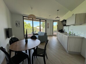 Un appartement moderne doté d’un coin repas, d’une cuisine et d’un balcon avec vue.