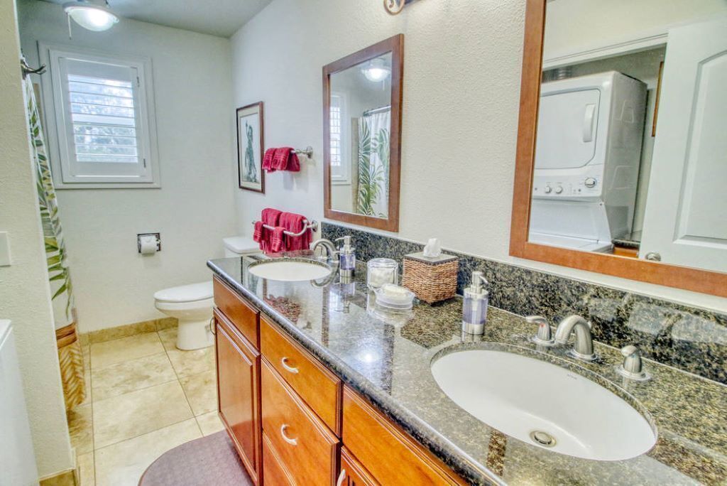 A bathroom with two sinks, a toilet, and a shower.