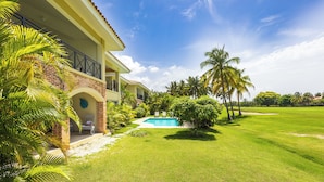 A large, two-story building with a swimming pool, surrounded by a well-maintained lawn and palm trees. - Family Elite Golf Vacations in Cocotal (Punta Cana)