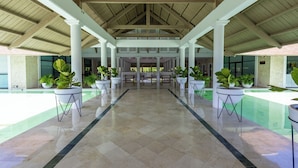 A covered outdoor area with a pool, potted plants, and a central seating area. - Family Elite Golf Vacations in Cocotal (Punta Cana)