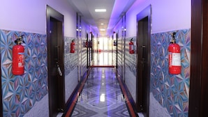 A hallway with patterned walls, fire extinguishers mounted on the walls, and a reflective floor. - Gokul Plaza (Bhubaneshwar)