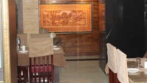 A dining area with a wooden wall, a framed artwork, and a table set for two. - Gokul Plaza (Bhubaneshwar)