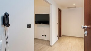 Une chambre dotée d’un téléviseur à écran plat fixé au mur, d’un téléphone mural et d’une porte en bois.