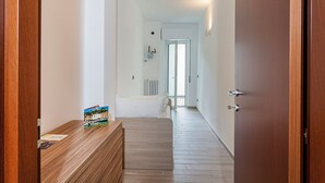 Un couloir avec un banc en bois, un radiateur et une porte donnant sur une pièce.