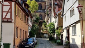 En brostensbelagt gade der fører hen til en kirke med et klokketårn.