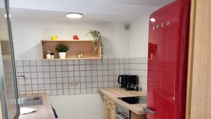 Et lille køkken med et rødt køleskab, træskabe, en vask og en kaffemaskine.