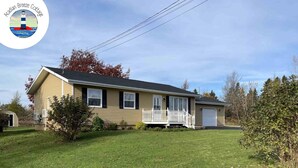 Ein eingeschossiges Haus mit Veranda, Garage und gepflegtem Rasen.