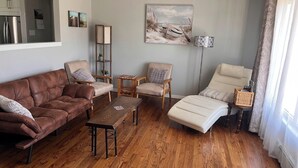 Ein Wohnzimmer mit einem braunen Ledersofa, einem beigen Liegesessel, einem Couchtisch aus Holz und einer Stehlampe.