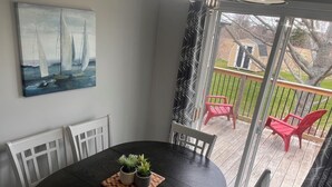 Ein Essbereich mit einem schwarzen Tisch, weißen Stühlen und einem Gemälde von Segelbooten.
