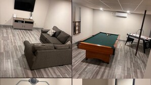 Ein Wohnzimmer mit einer Couch, einem Billardtisch und einem Kicker.