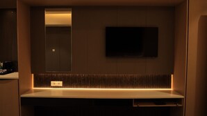 Une salle de bain moderne avec un grand miroir, un téléviseur à écran plat fixé au mur et un élégant plan de toilette.