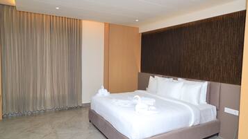 A hotel room with a large bed, a wooden headboard, a curtain, and a marble floor.