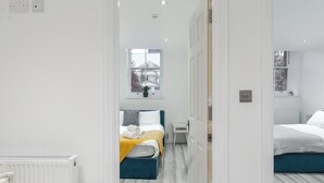 A modern bedroom with a large bed, a smaller bed, and a window. - Beautiful Flat in London- Close to Central London- Canary Wharf- London ExCel (London)