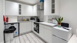 A modern kitchen with white cabinets, a built-in washing machine, a dishwasher, and a compact refrigerator. - Beautiful Flat in London- Close to Central London- Canary Wharf- London ExCel (London)