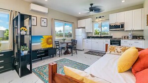 A modern room with a bed, a desk, a chair, and a small kitchen area. - Hilo Town Center Studio (Hilo)