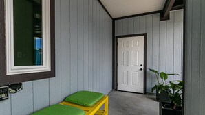A room with a bench, a door, and a potted plant. - Hilo Town Center Studio (Hilo)