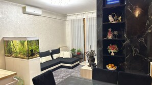 Ein Wohnzimmer mit einem schwarz-weißen Sofa, einem großen Aquarium, einem Esstisch und einer schwarzen Marmorablage mit Dekoration.