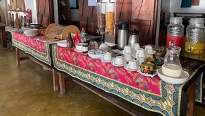 A dining area with a long table set for a meal, featuring a variety of dishes, drinks, and a coffee station. - Milele beach resort  (Dongwe)