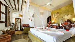 A bedroom with a large bed, a ceiling fan, and a bedside table with a lamp. - Milele beach resort  (Dongwe)