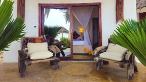 A room with a bed, a wooden bench, and a view of the beach. - Milele beach resort  (Dongwe)