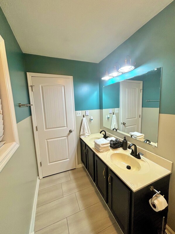 A bathroom with two sinks, a large mirror, and a white door. - Pine Hollow w/HotTub · Fireplace · Games · KingBed · Pet Friendly · Hiking (Albrightsville)
