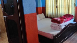 A room with a bed, a wooden door, and a toilet. - SS Hotel Kings & Lodge Charikot Dolakha (Bhimeshwar)