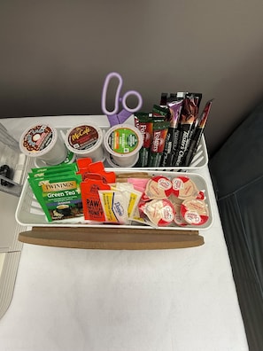 Un plateau contenant divers aliments, notamment du café instantané, du thé et des en-cas.