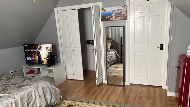 Ein Schlafzimmer mit einem Bett, einem Fernseher, einem Kleiderschrank und einem Spiegel.