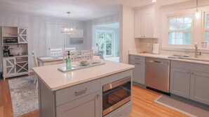 Una cocina moderna con gabinetes grises, horno empotrado y una isla grande con pileta.