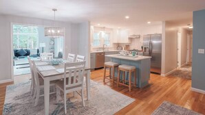 Una cocina moderna con una isla central, armarios blancos y electrodomésticos de acero inoxidable.