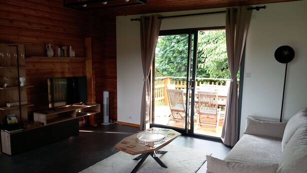 A cozy living room with a wooden interior, a sofa, a coffee table, and a TV on a wooden stand.