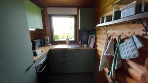 A compact kitchen with a window, wooden walls, and basic amenities.