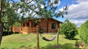A wooden cabin with a deck and a hammock in the yard.