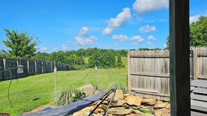 A backyard with a wooden fence, a lawn, and a stone wall. - #5 getaway cabin 
 (New Lexington)