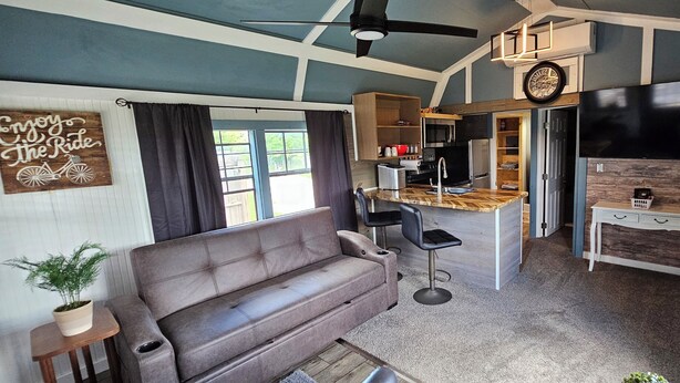 A compact living space with a sofa, a kitchenette, and a dining area. - #5 getaway cabin 
 (New Lexington)
