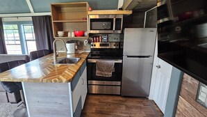 A compact kitchen with a wooden countertop, stainless steel appliances, and a built-in oven. - #5 getaway cabin 
 (New Lexington)