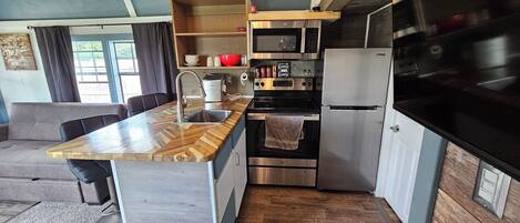 A compact kitchen with a wooden countertop, stainless steel appliances, and a built-in oven.