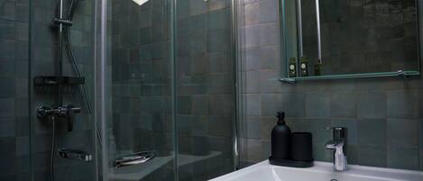 A modern bathroom with a glass shower enclosure, a white sink, and a mirror above the sink.