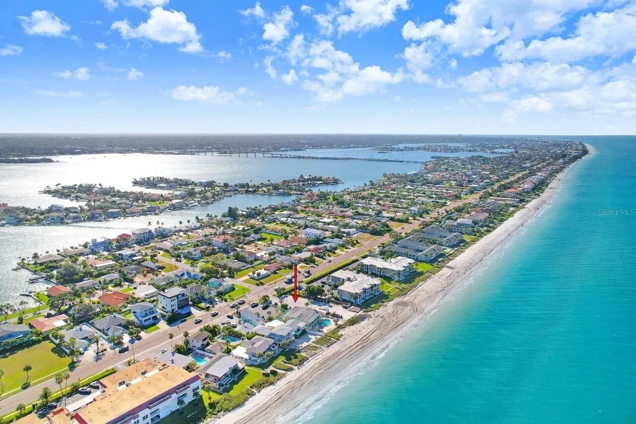 Vista aérea de una zona residencial costera con casas, carreteras y una playa.