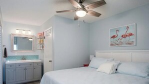 Ein Schlafzimmer mit Bett, Deckenventilator, Nachttisch und einem an der Wand befestigten Spiegel.