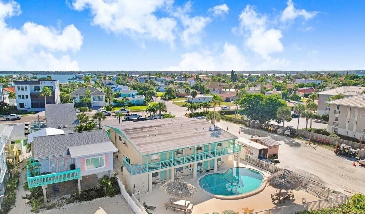 A coastal hotel with a pool, multiple buildings, and a view of the sea.