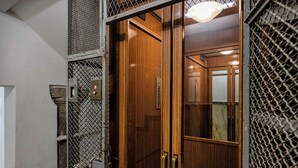 A wooden door with a metal mesh panel and a light fixture above it. - Casa Alma by Wonderful Italy (Genoa)