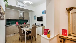 A modern kitchen with a dining area, a flat-screen TV, and a decorative mirror. - Casa Alma by Wonderful Italy (Genoa)