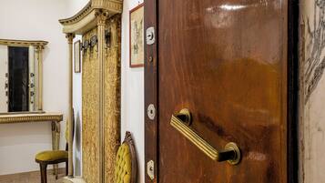 A wooden door with a brass handle, a mirror with a gold frame, and a patterned curtain.