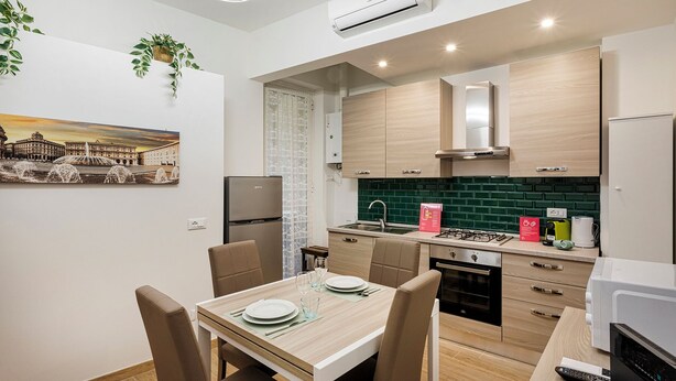A modern kitchen with a dining area, featuring a built-in oven, a gas stove, and a refrigerator. - Casa Alma by Wonderful Italy (Genoa)