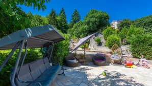 Une terrasse avec un fauteuil suspendu, des sièges d’extérieur, un fauteuil suspendu et un vélo.