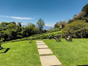 A garden pathway with stepping stones leading to a seating area with chairs. - Peaceful Mountain Experience - Coyote House (Poás)